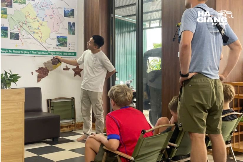 A local driver explaining the Ha Giang Loop map at a junction on the plateau