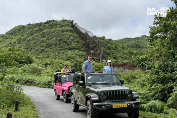 Jeep waiting at the Lung Khuy Cave parking area with soft top folded and day packs on the seats