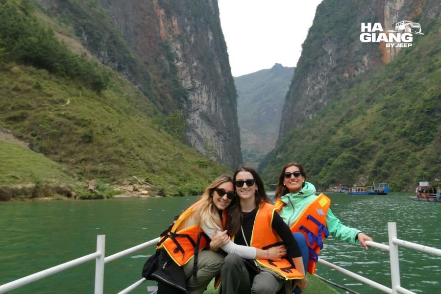 Small boat cruising through Tu San Canyon on the Nho Que River