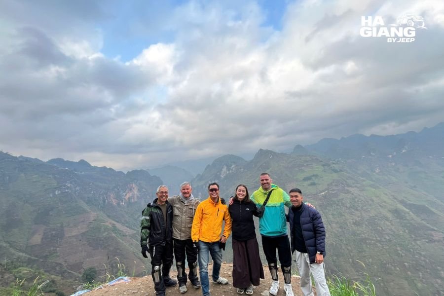 Travelers in warm jackets at a cold viewpoint on the Ha Giang Loop in winter