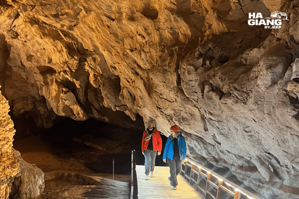 Wooden walkway and lit stalactites inside the first chamber of Lung Khuy Cave in Ha Giang