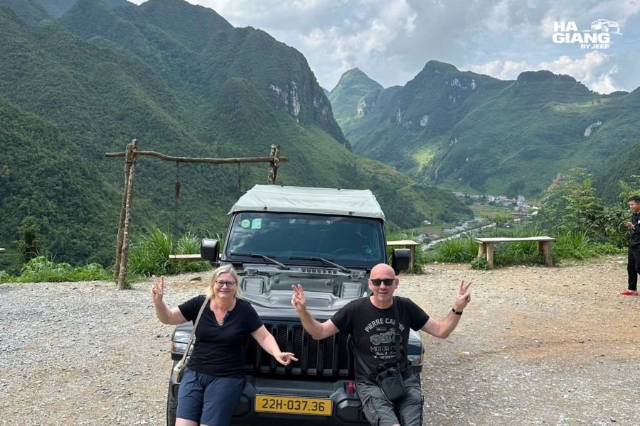 An older couple sitting with tea at a Ha Giang viewpoint beside the jeep