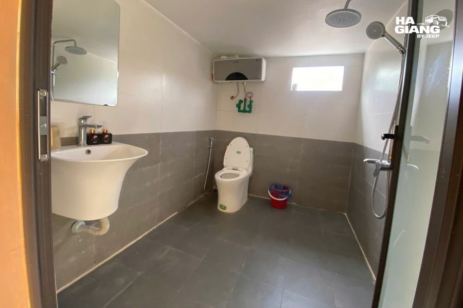 Clean homestay bathroom with squat toilet and basic shower setup, mountain village style
