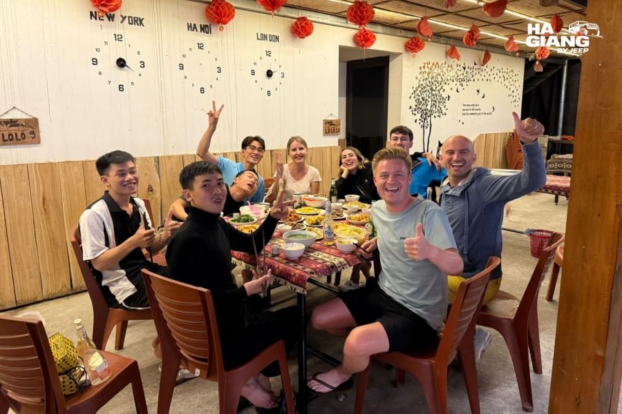 Group of twelve at a long homestay dinner table in Ha Giang
