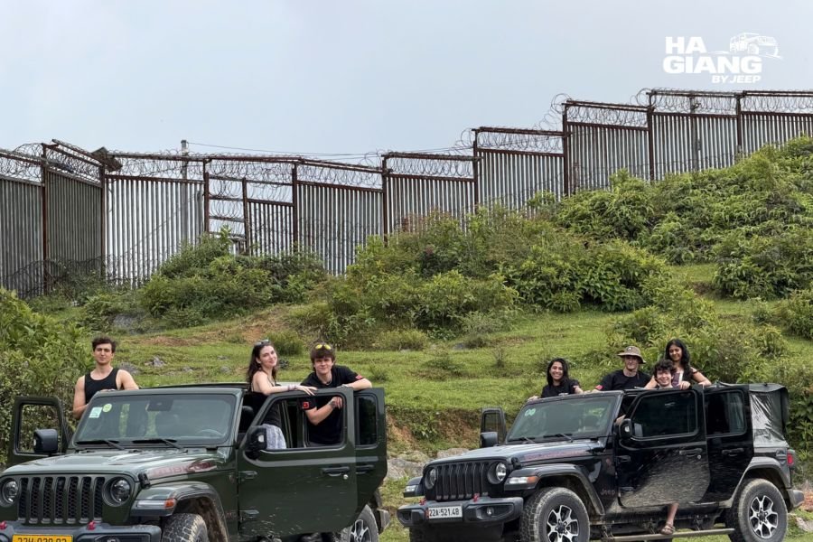 Ha Giang jeep Wrangler parked on mountain pass with backpacks and luggage, scenic valley landscape