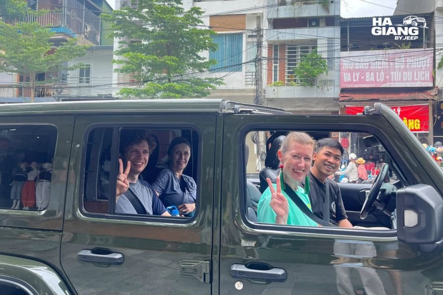 Private Jeep Wrangler parked at a central Hanoi hotel entrance, ready to pick up travelers for the journey to Ha Giang