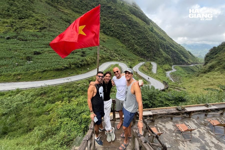 Winding mountain road with scenic curves approaching Ha Giang, showing dramatic valley views and steep terrain