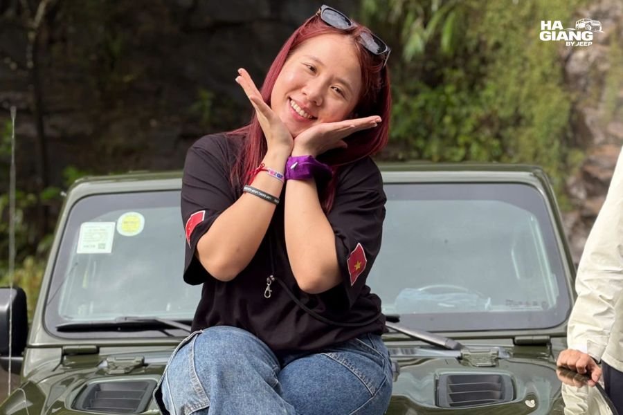 Solo female traveler standing confidently in front of open-air jeep in Ha Giang mountains