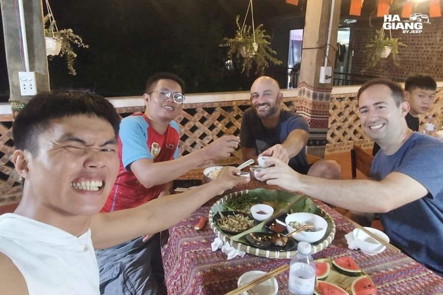 Travelers and a local host sharing a homestay dinner in Ha Giang