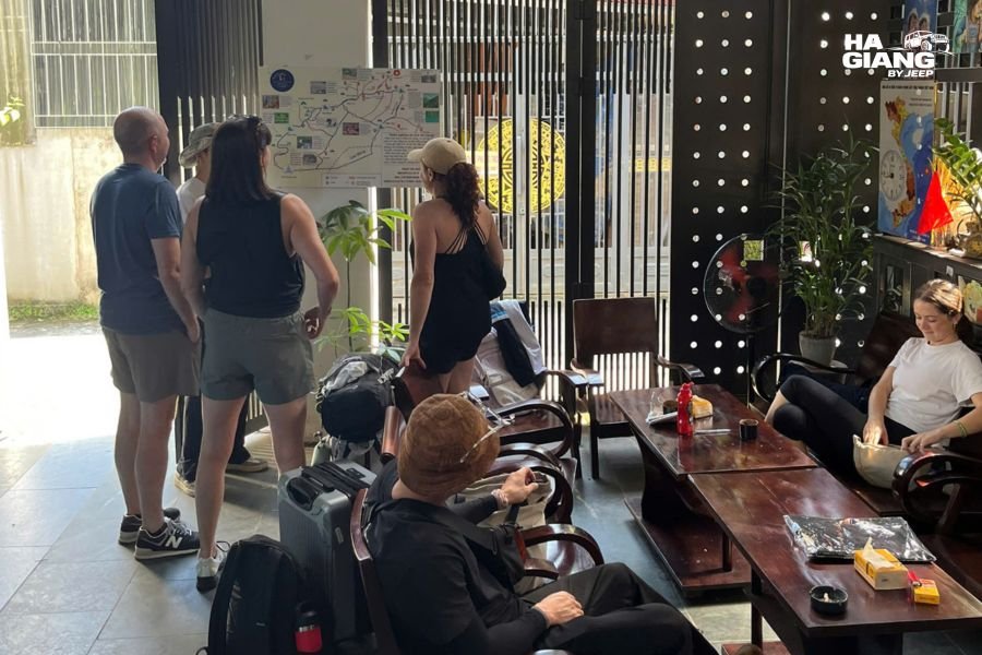 Travelers checking phones at a homestay table in Ha Giang after a day on the Loop