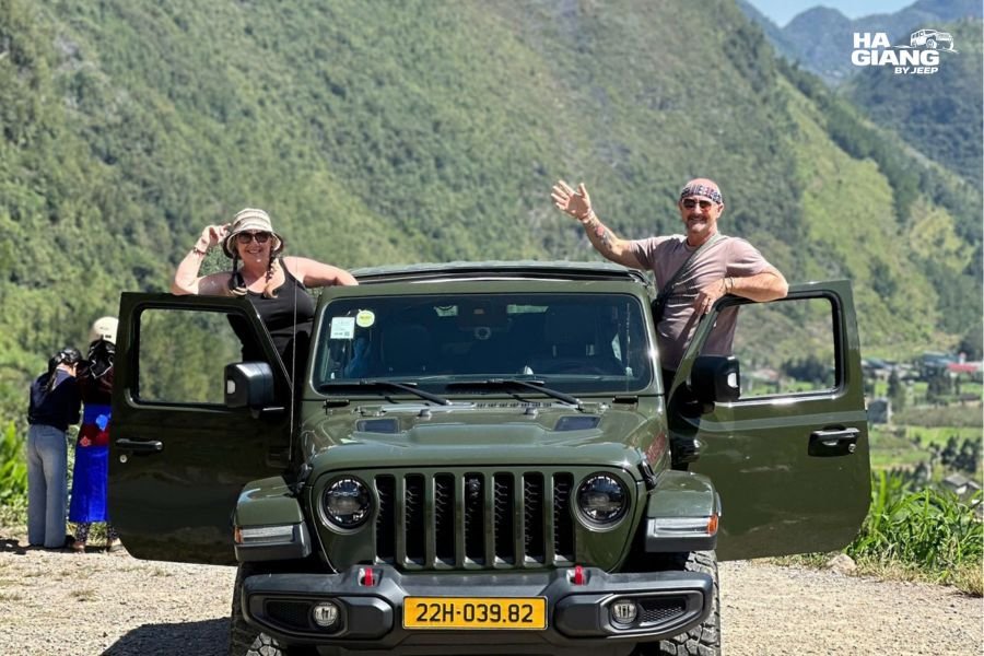 Ha Giang jeep tour in January: travelers in winter gear at a karst plateau viewpoint