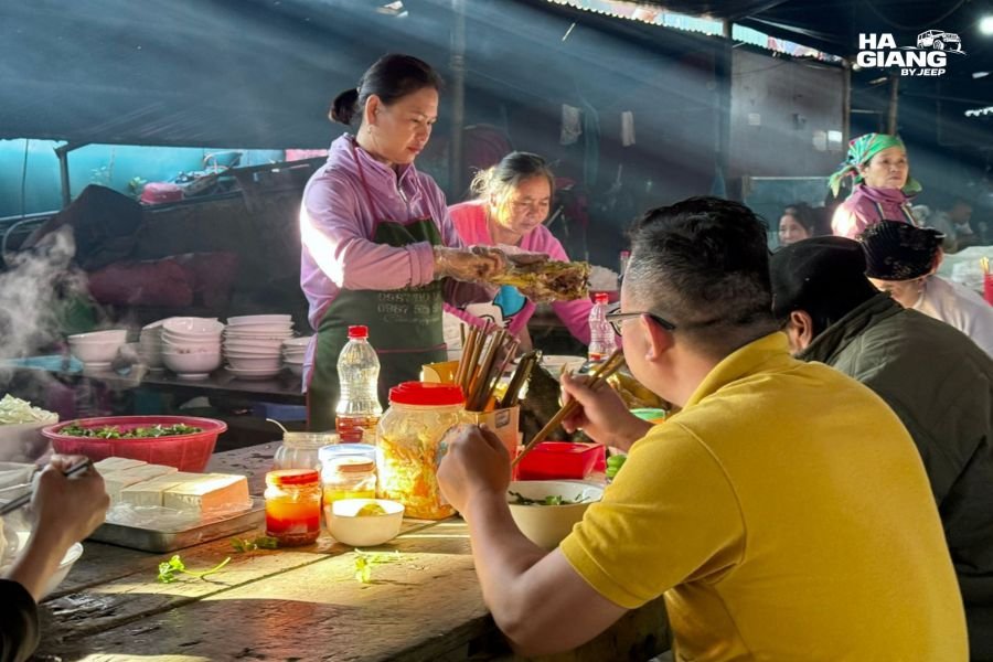 Hmong people eating together at a highland market in Ha Giang